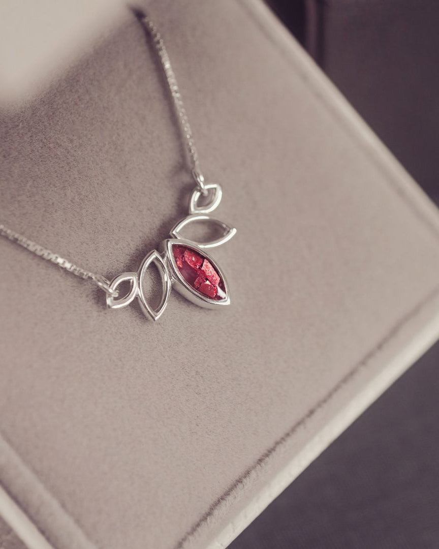 Silver necklace with a red gemstone pendant on a gray surface