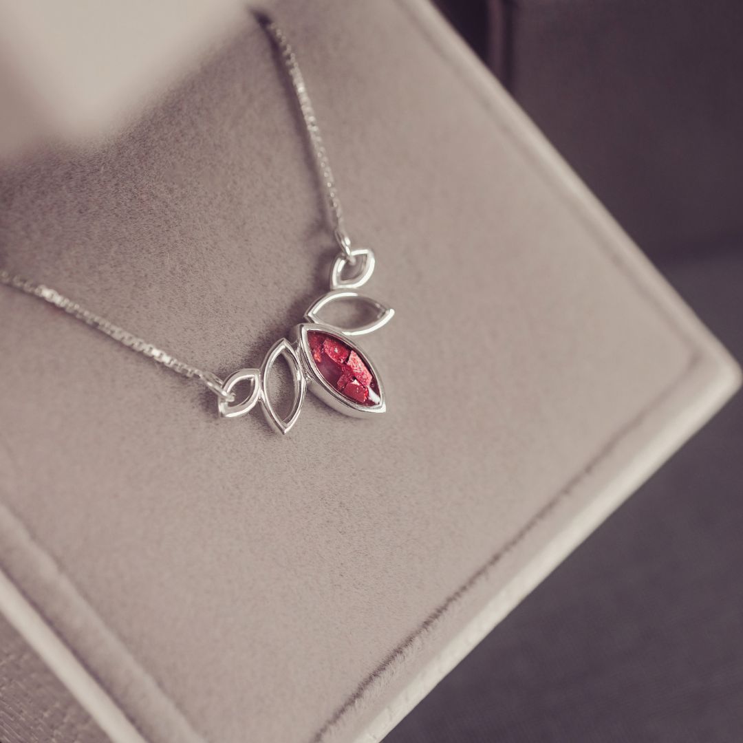 Silver necklace with a red gemstone pendant on a gray surface