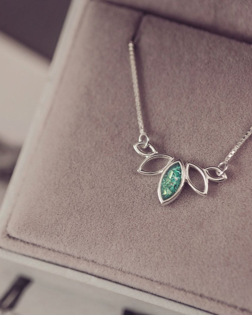 Silver necklace with a green gemstone pendant on a soft surface