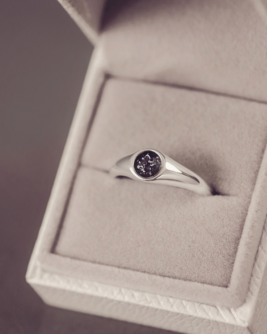 Silver ring with a purple gemstone in a jewelry box