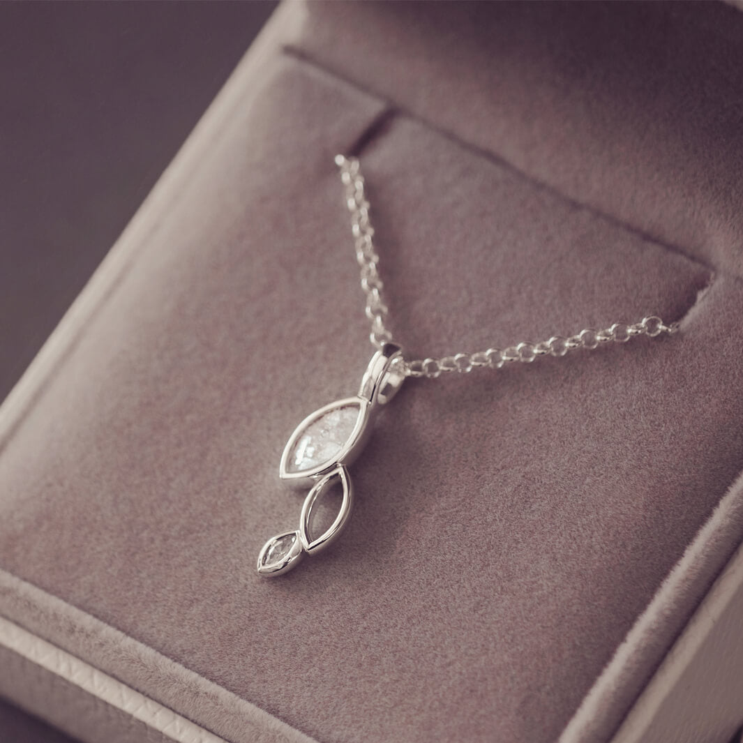 sterling silver necklace featuring gem stone, cremation ashes, clear crystal and resin laying in a grey jewellery box