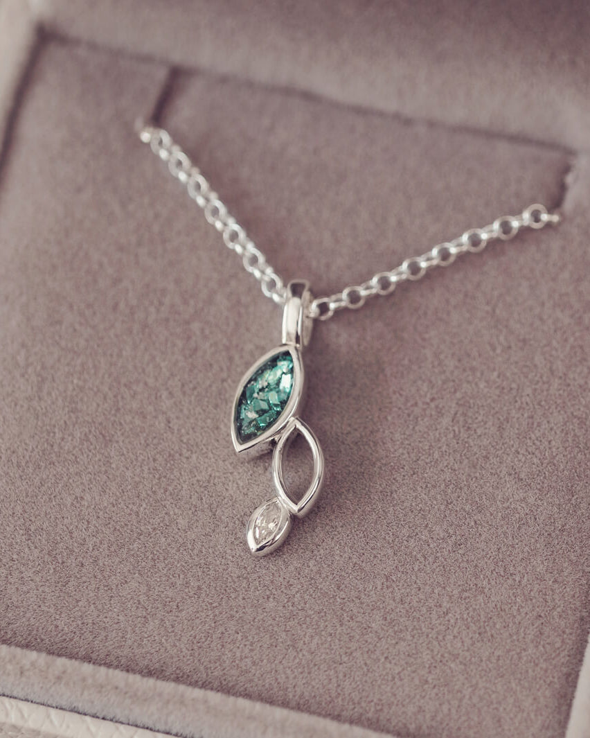 sterling silver necklace featuring gem stone, cremation ashes, green crystal and resin sat in a grey jewellery box