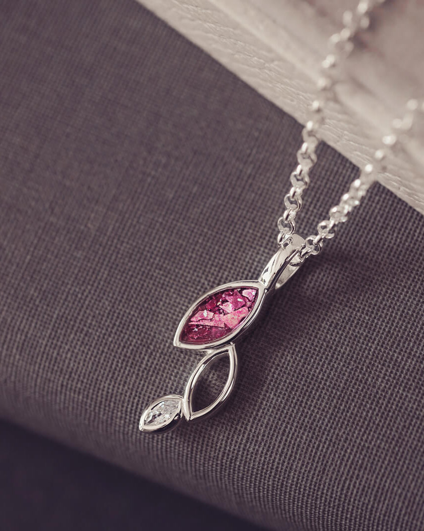sterling silver necklace featuring gem stone, cremation ashes, pink crystal and resin sat on a grey back ground