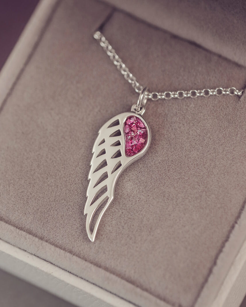 Silver Angel Wing Necklace with pink floating crystals which hold cremation ashes. Shown in a grey jewellery box