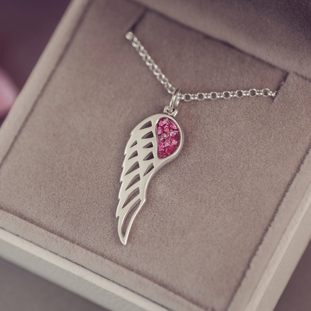Silver Angel Wing Necklace with pink floating crystals which hold cremation ashes. Shown in a grey jewellery box