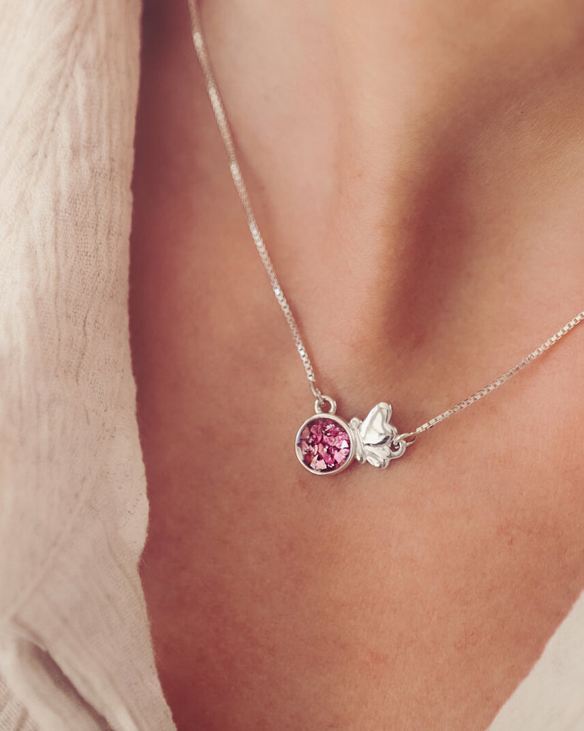 Sterling Silver Butterfly Shaped Necklace filled with pink crystals and cremation ashes, on a silver chain worn round a ladies neck