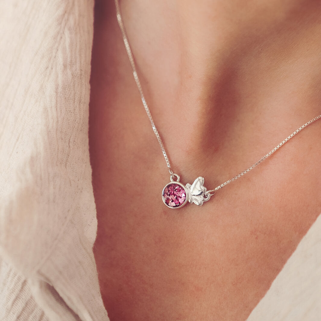 Sterling Silver Butterfly Shaped Necklace filled with pink crystals and cremation ashes, on a silver chain worn round a ladies neck