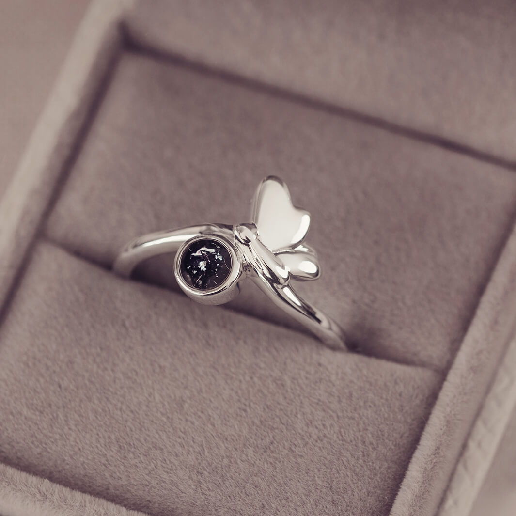 Silver butterfly ring with black floating crystals and cremation ashes in a grey jewellery box