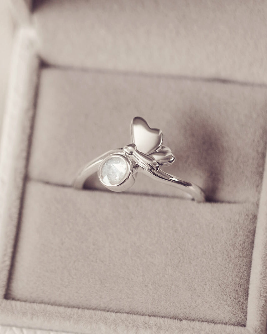 Silver butterfly ring, with clear crystals and cremation ashes. In a grey jewellery box.