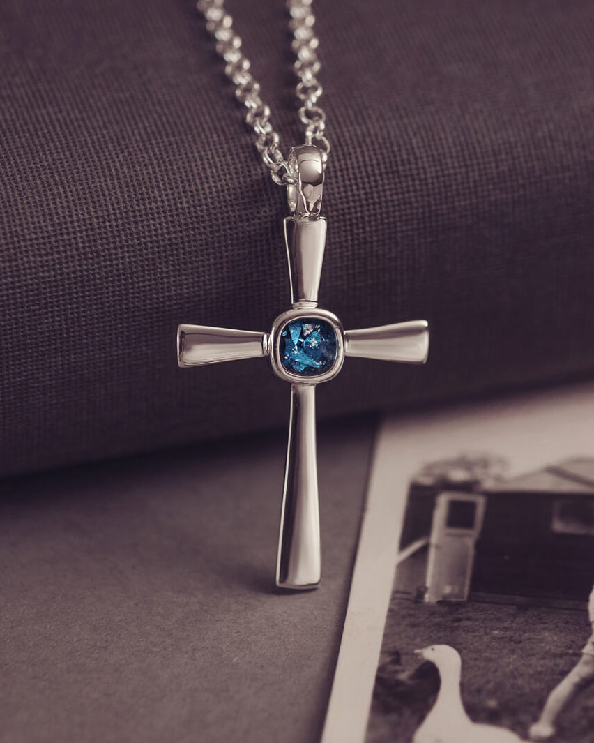 silver cross necklace with a section of resin and blue crystals, holding memorial ashes