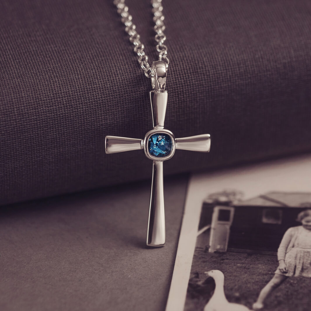 silver cross necklace with a section of resin and blue crystals, holding memorial ashes