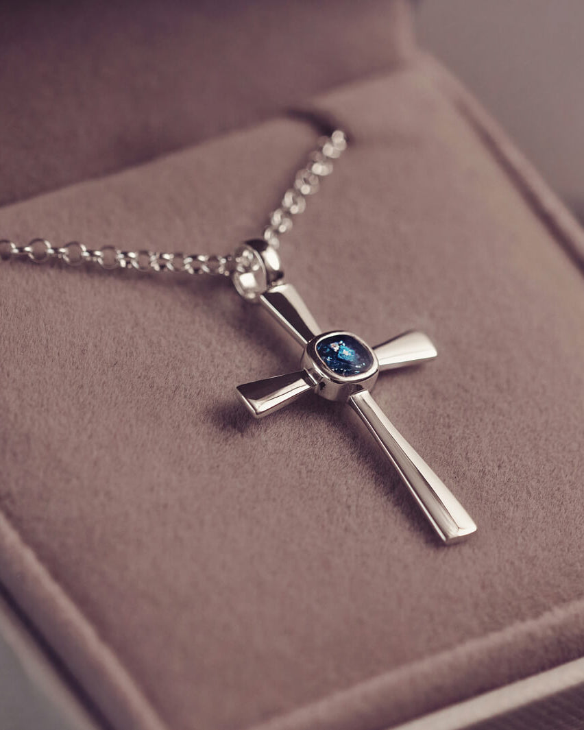 silver cross necklace with a section of resin and blue crystals, holding memorial ashes