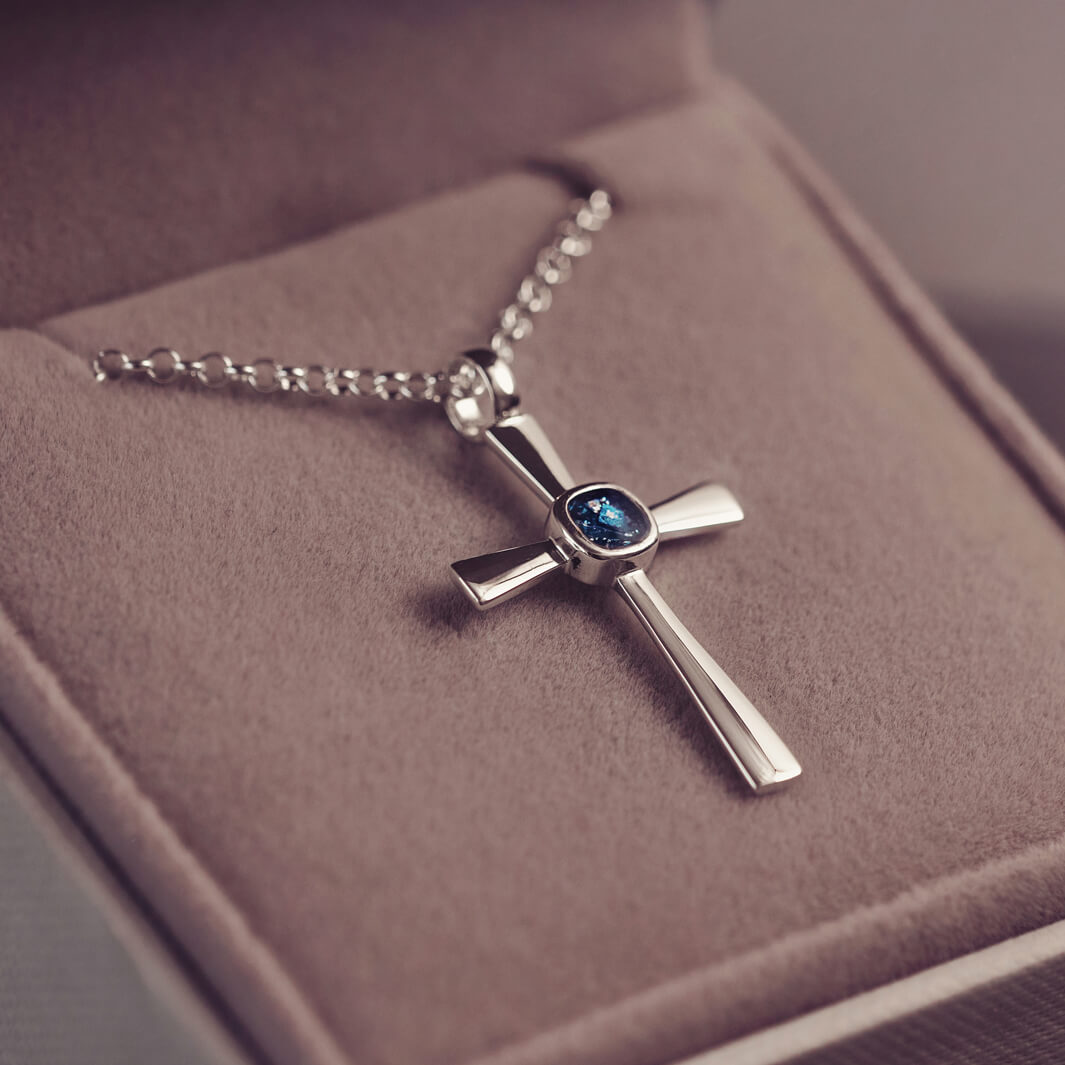 silver cross necklace with a section of resin and blue crystals, holding memorial ashes