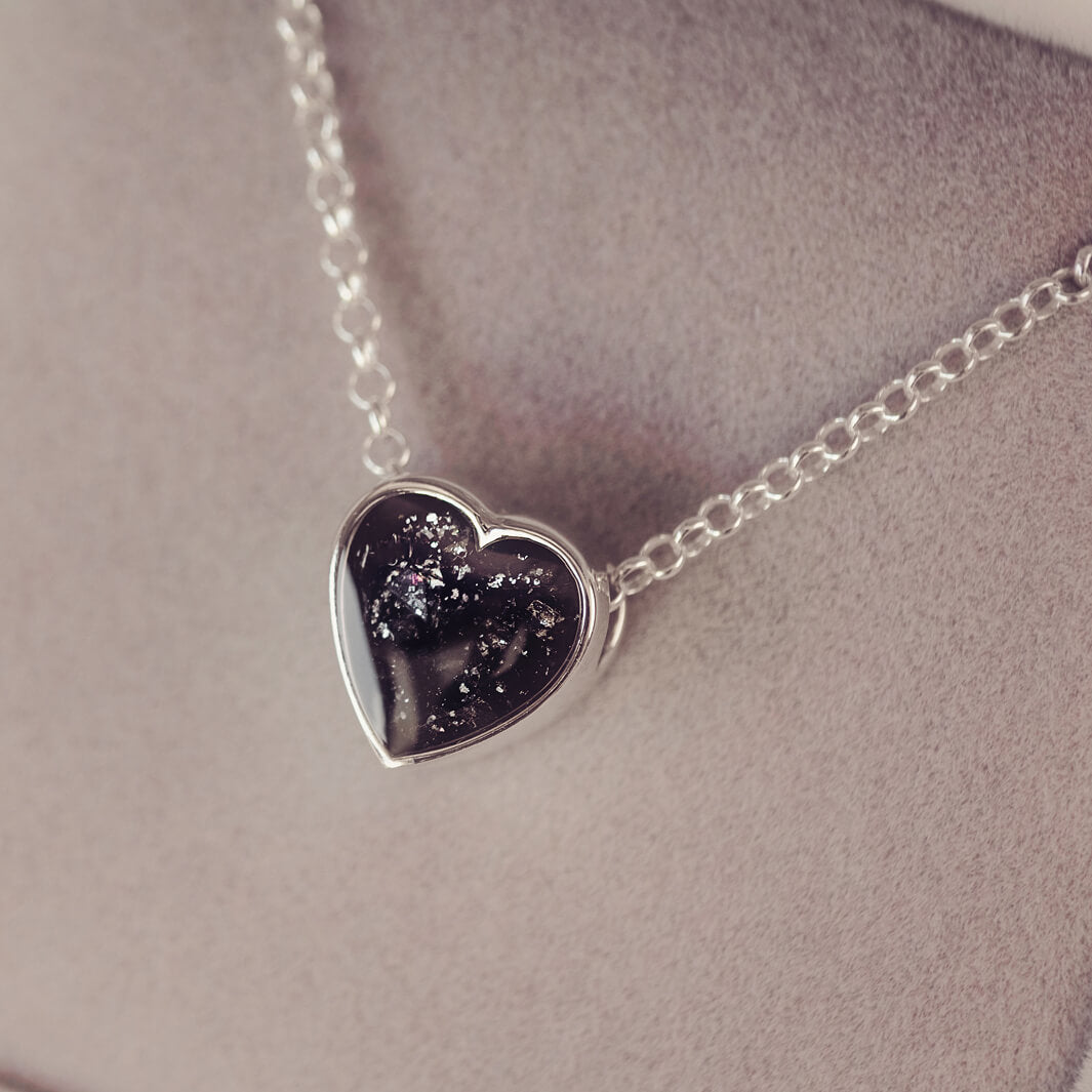 black heart pendant, filled with crystals, glitter and memorial ashes, on a silver chain.