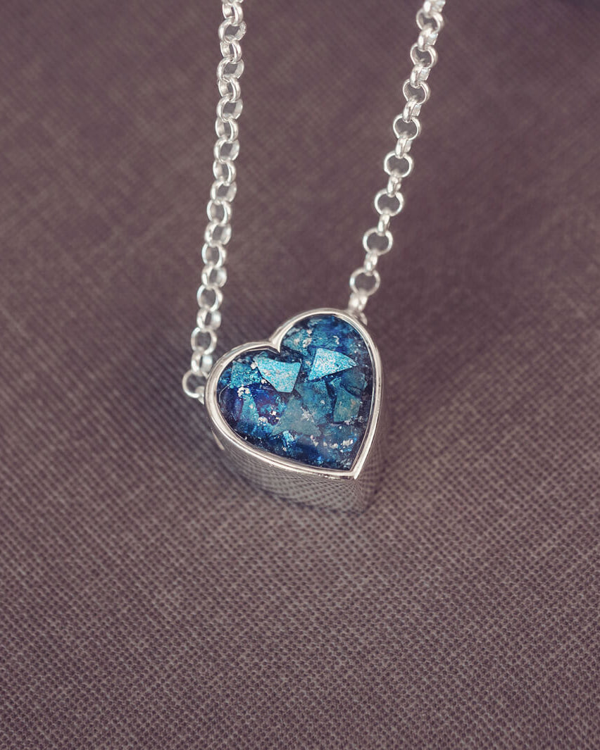 Blue heart pendant, filled with crystals, glitter and memorial ashes, on a silver chain.