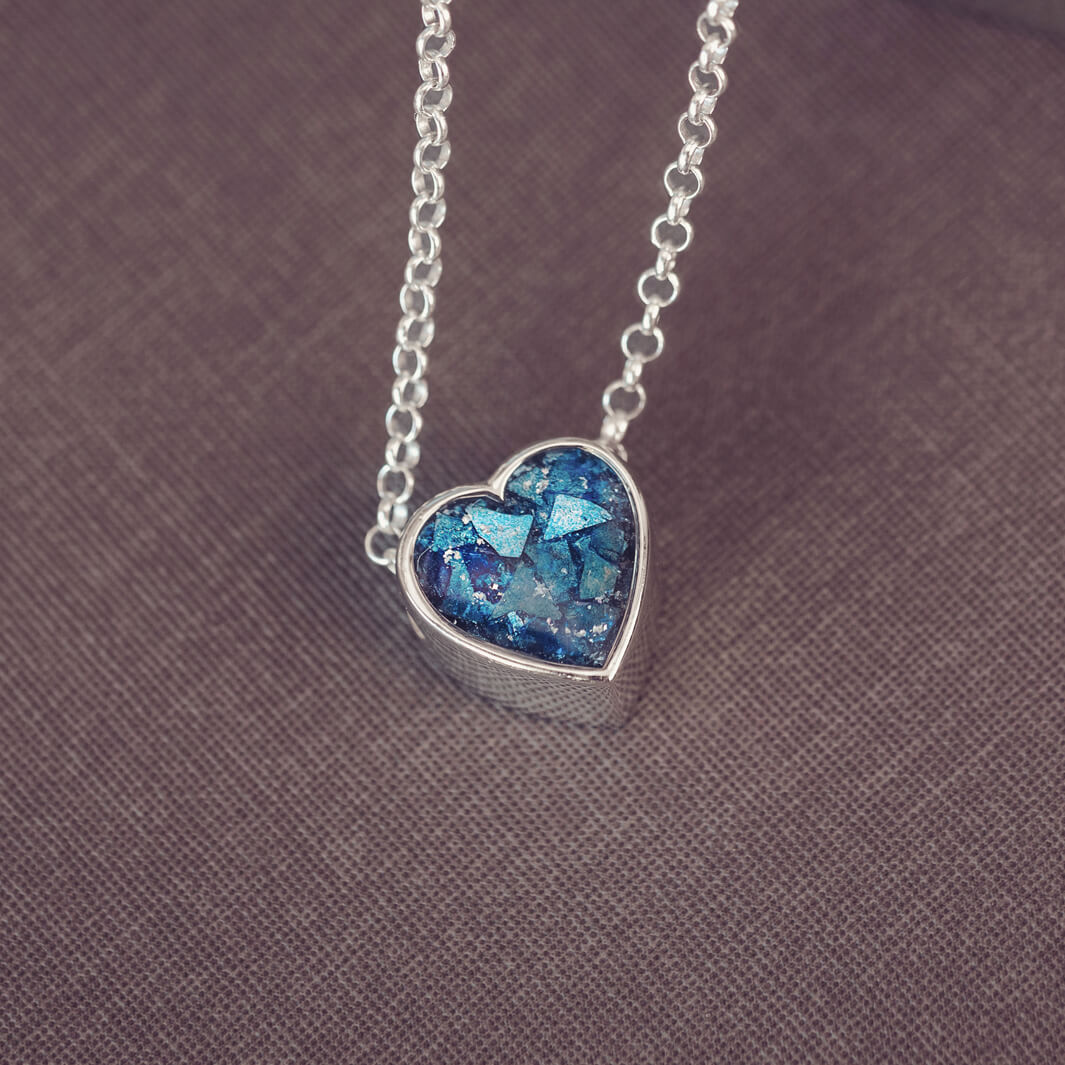 Blue heart pendant, filled with crystals, glitter and memorial ashes, on a silver chain.