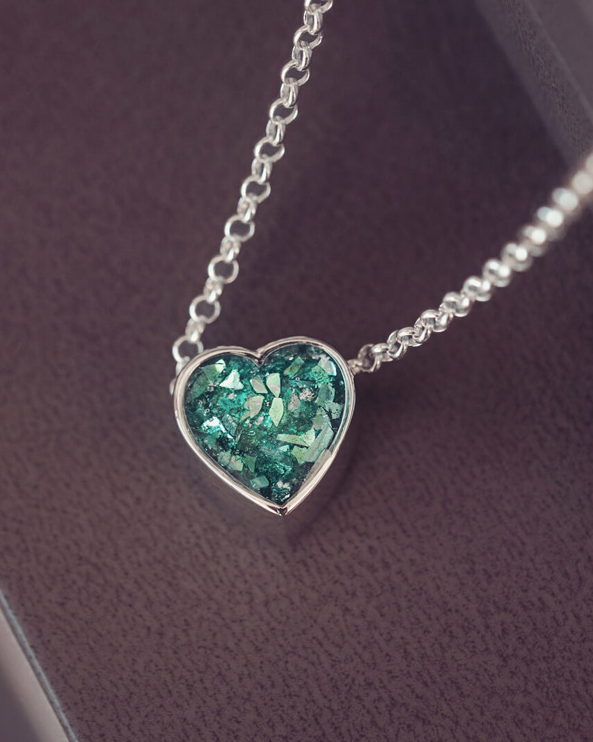 Green heart pendant, filled with crystals, glitter and memorial ashes, on a silver chain.