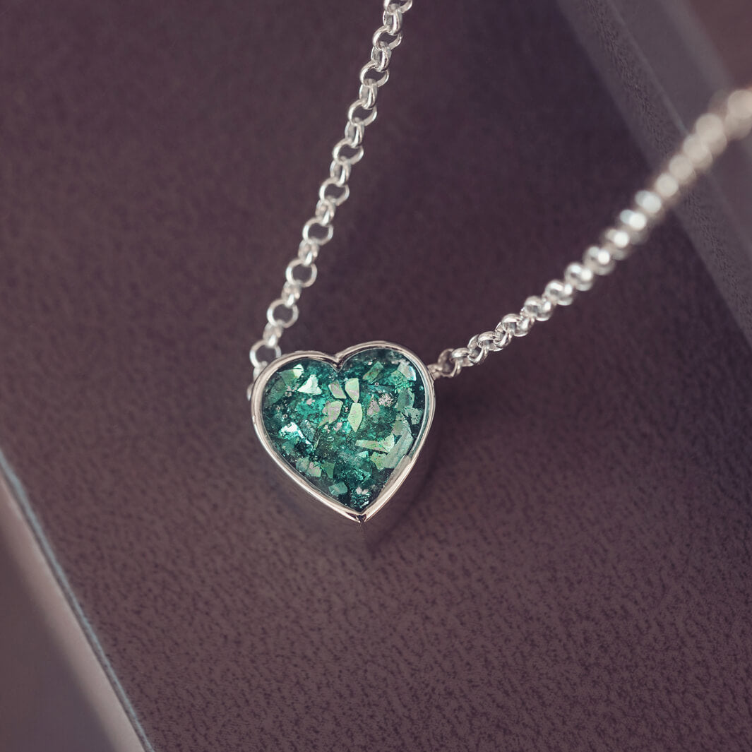 Green heart pendant, filled with crystals, glitter and memorial ashes, on a silver chain.