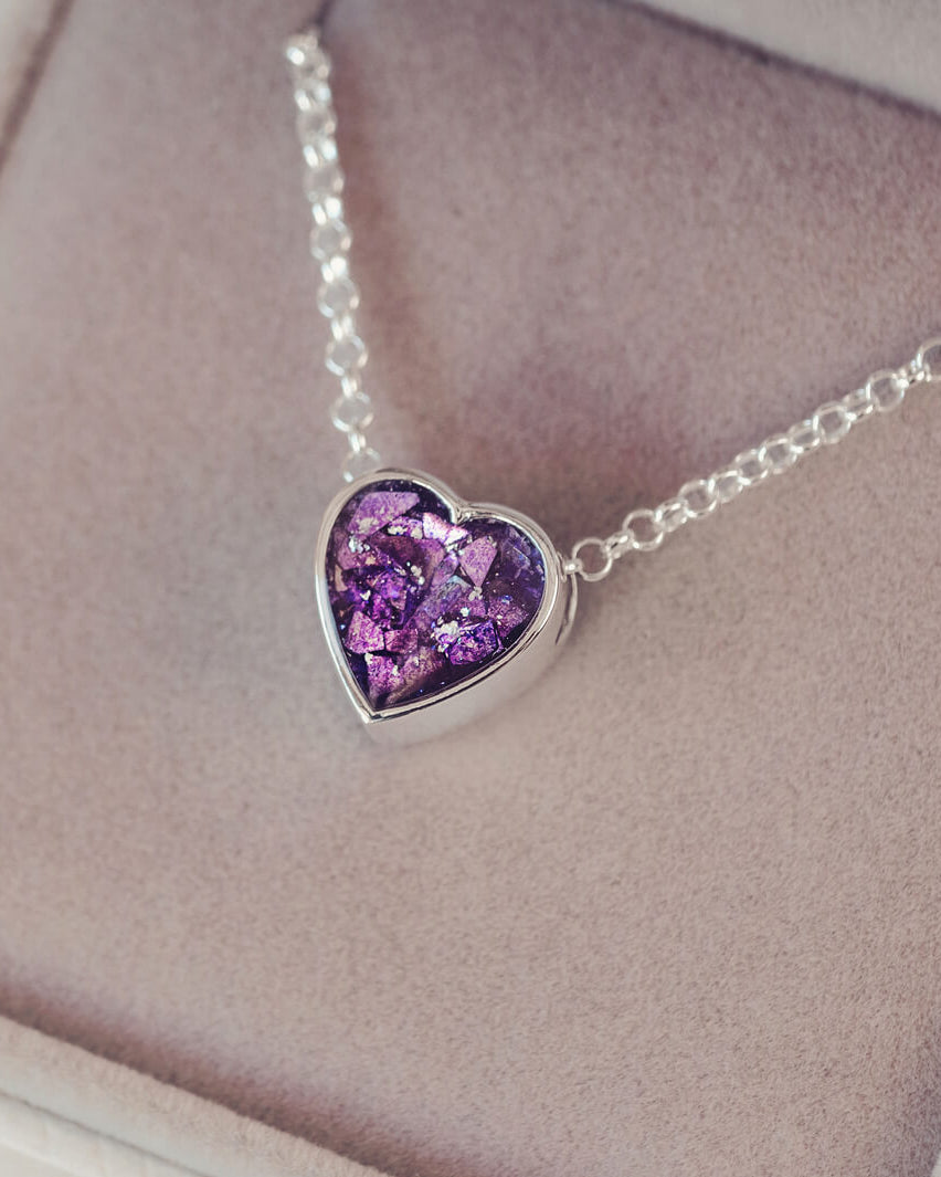purple heart pendant, filled with crystals, glitter and memorial ashes, on a silver chain.