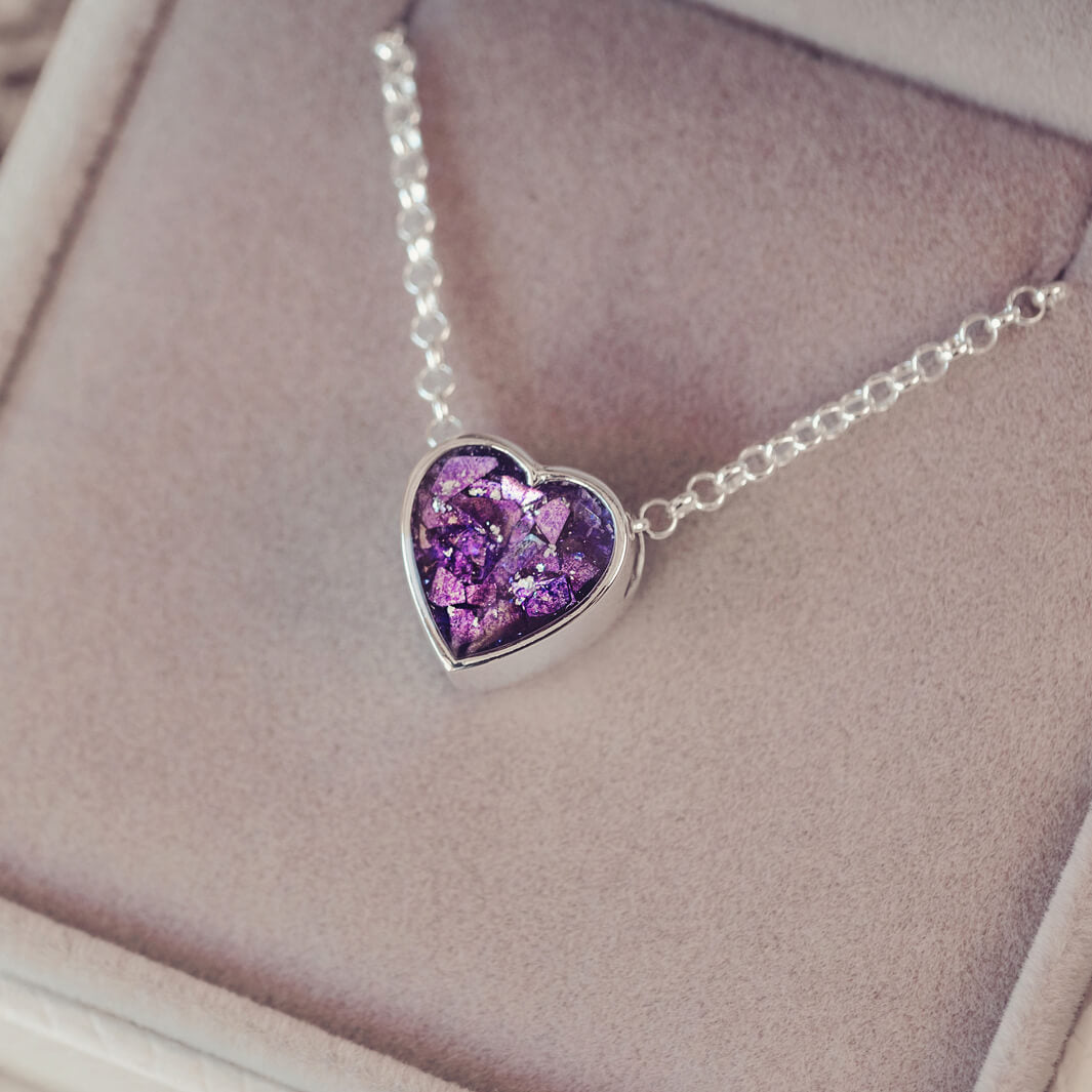 purple heart pendant, filled with crystals, glitter and memorial ashes, on a silver chain.