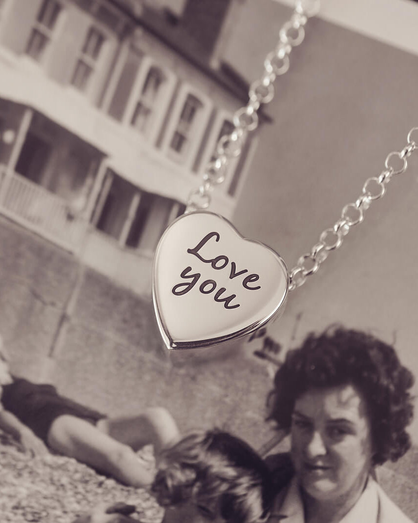 Silver heart pendant on a silver chain with the message 'Love you' engraved on the reverse