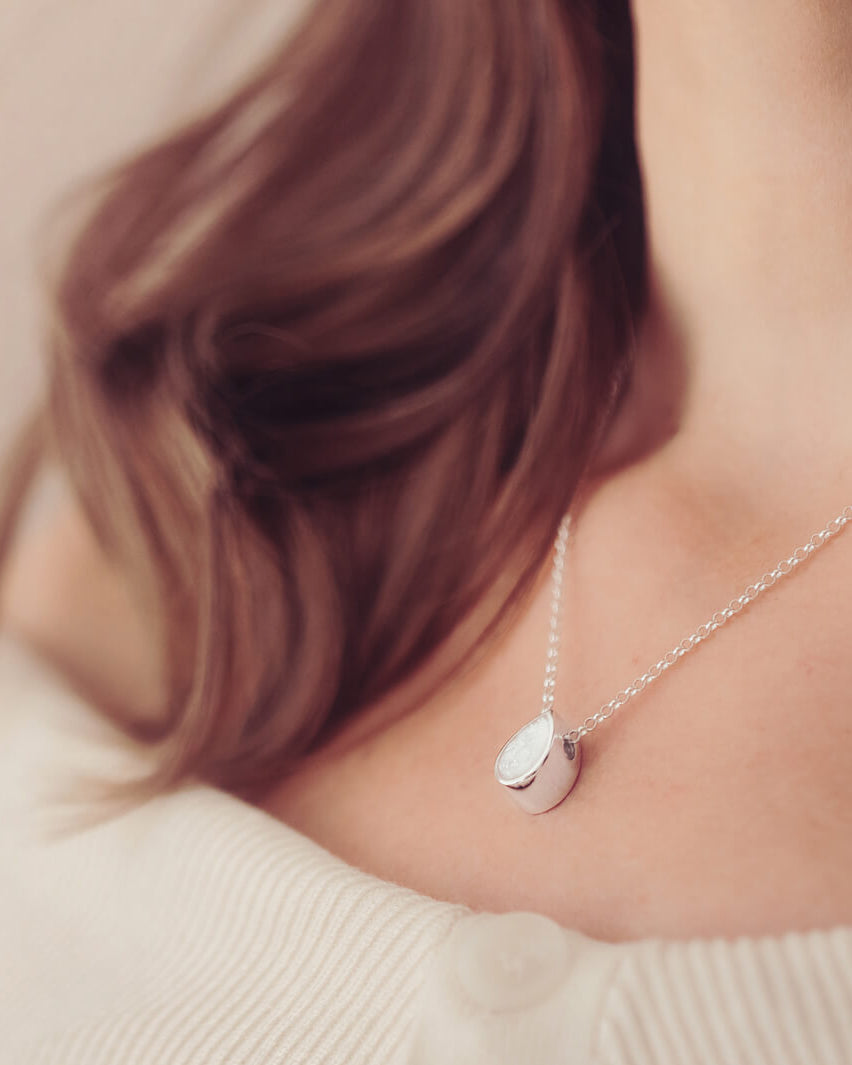 Cremation Ashes Floating Peardrop Necklace, in clear, on a sterling silver chain on a ladies neck