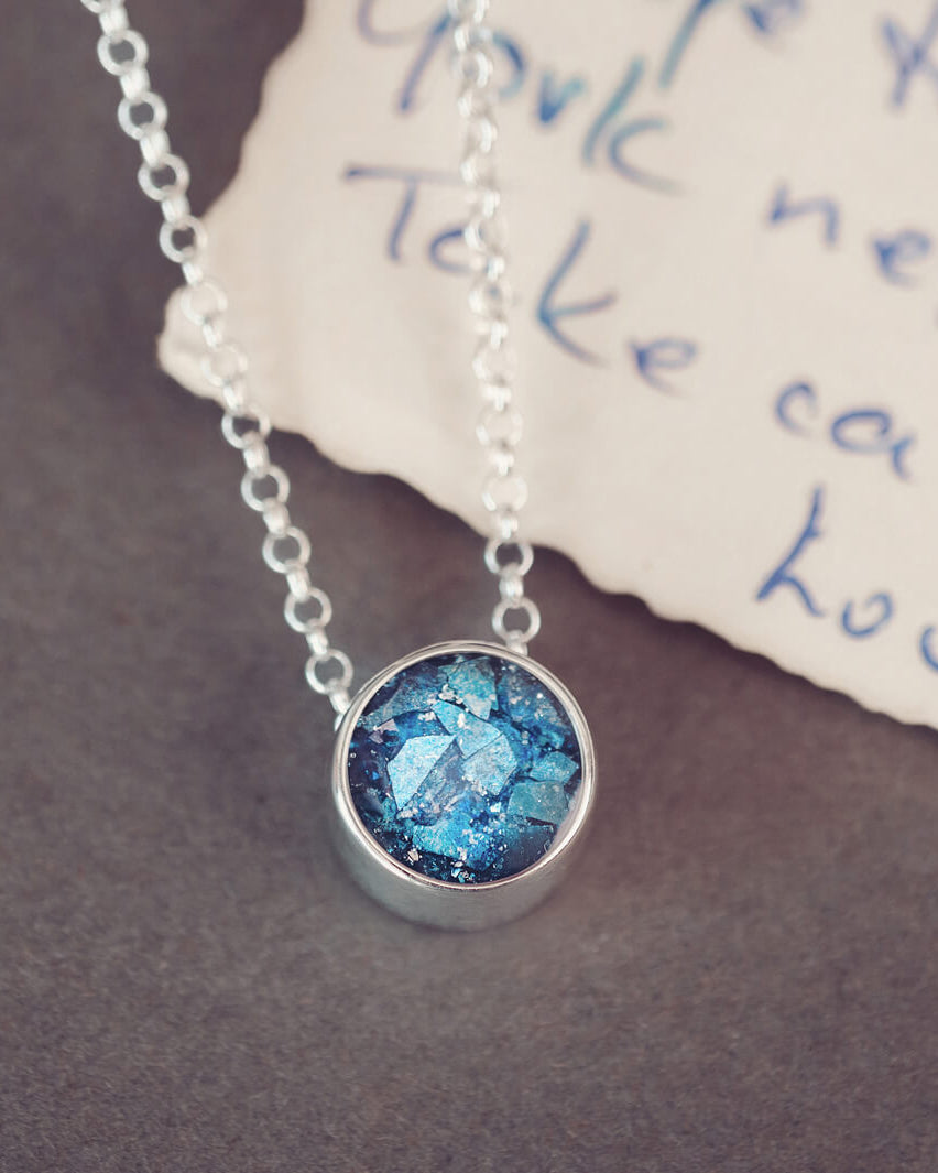 Round silver charm on silver chain, filled with blue crystal, glitter, resin & ashes.
