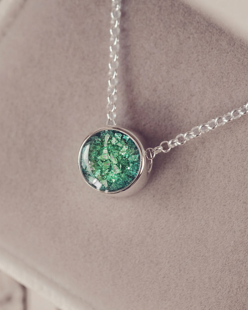 Round silver charm on silver chain, filled with green crystal, glitter, resin & ashes.