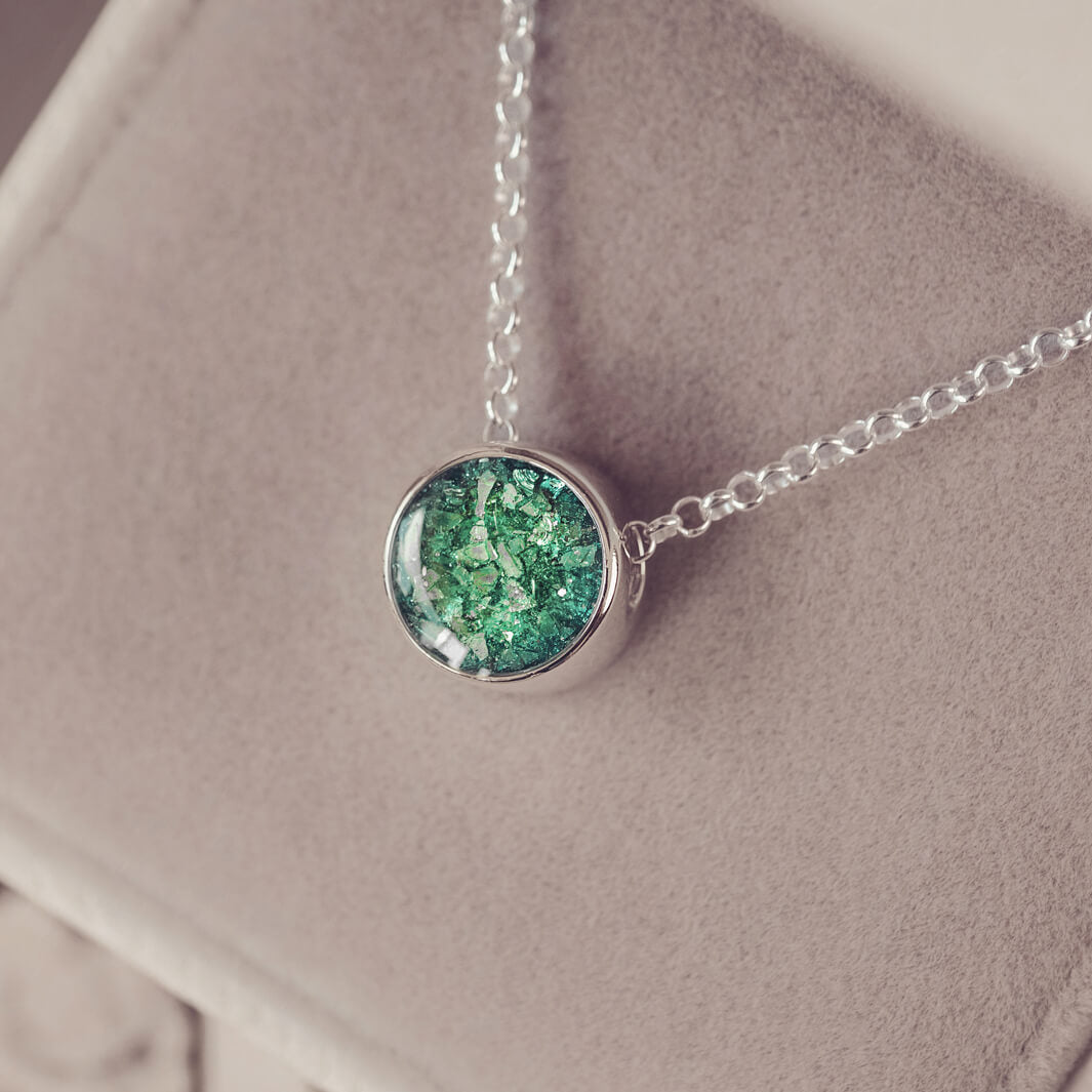 Round silver charm on silver chain, filled with green crystal, glitter, resin & ashes.