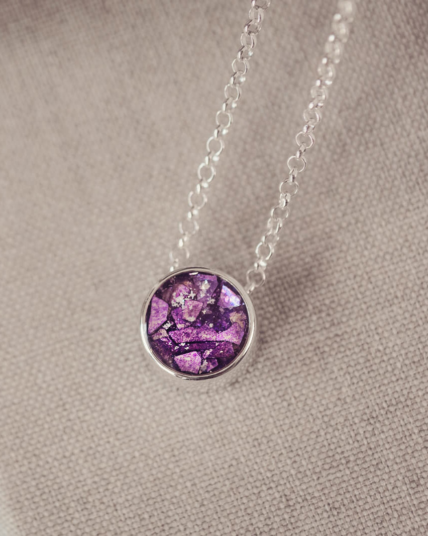 Round silver charm on silver chain, filled with purple crystal, glitter, resin & ashes.