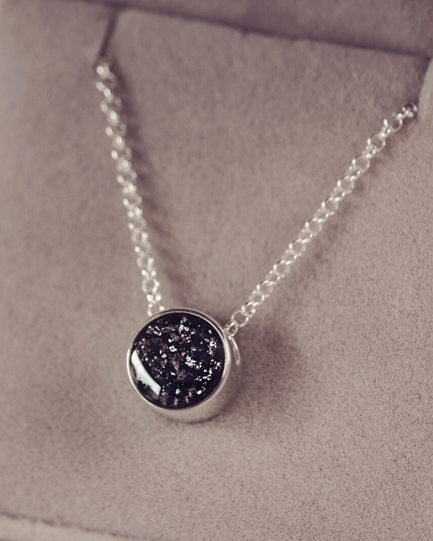 Round silver charm on silver chain, filled with black crystal, glitter, resin & ashes.