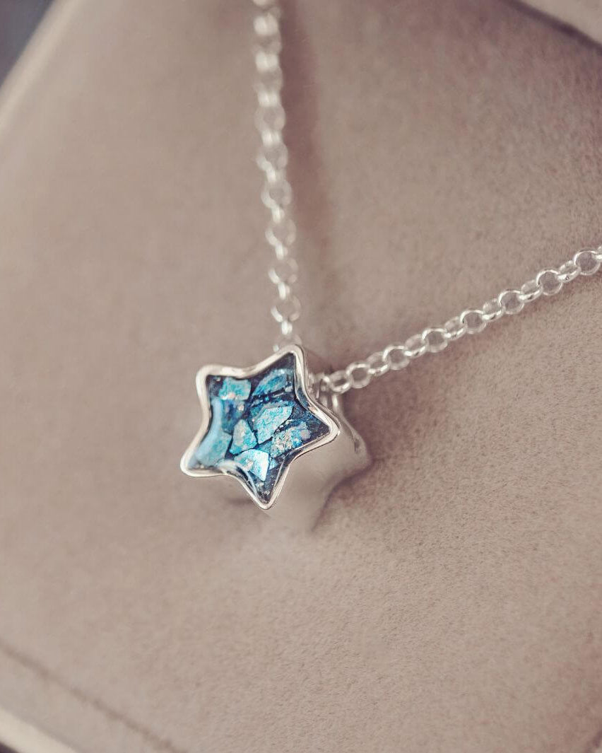 Star-shaped pendant necklace with blue gemstone on a soft surface