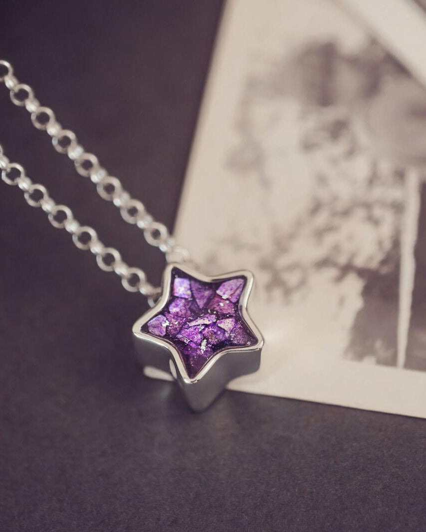 Star-shaped purple pendant on a chain against a blurred background