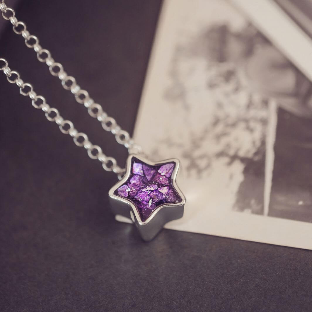 Star-shaped purple pendant on a chain against a blurred background