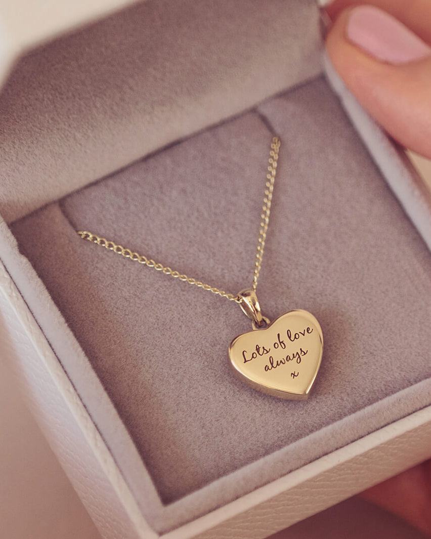 gold heart necklace filled on a gold chain, showing an engraved message of 'lots of love always x' on the reverse