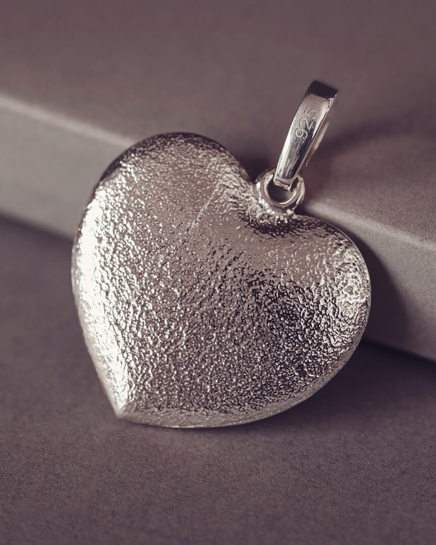 The dimpled reverse of a Sterling silver Large Heart necklace, displayed on a grey background.
