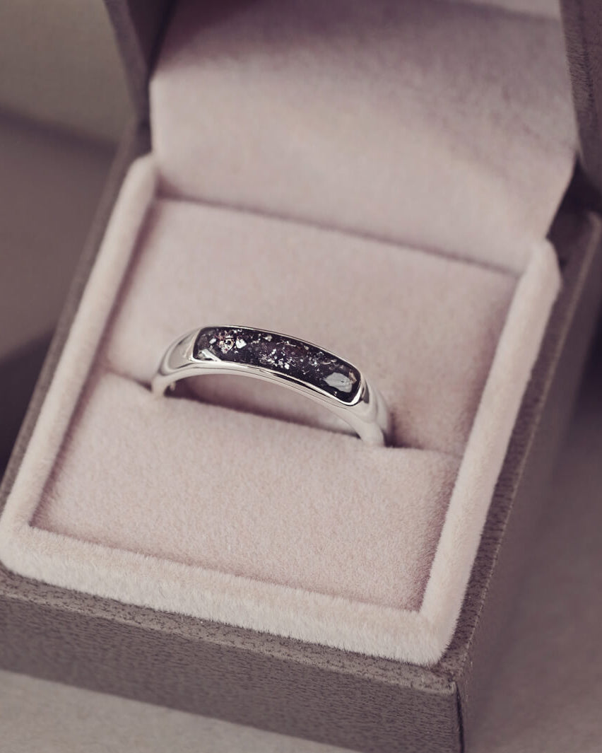 Sterling silver Mens Band Ring with a central section filled with memorial ashes and black crushed crystals, displayed in a grey jewellery box