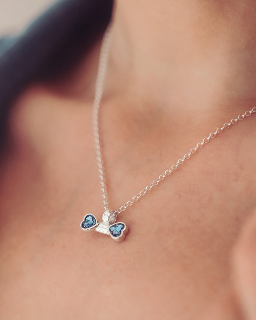 sterling silver bone shaped necklace, filled with cremation ashes, blue crystal and resin on a silver chain around a ladies neck