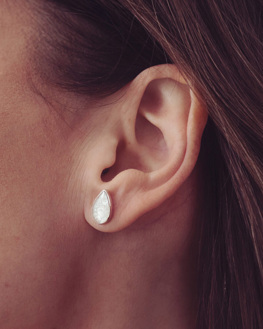 Cremation Ashes Teardrop Earrings with blue crystal, being worn in a ladies ear