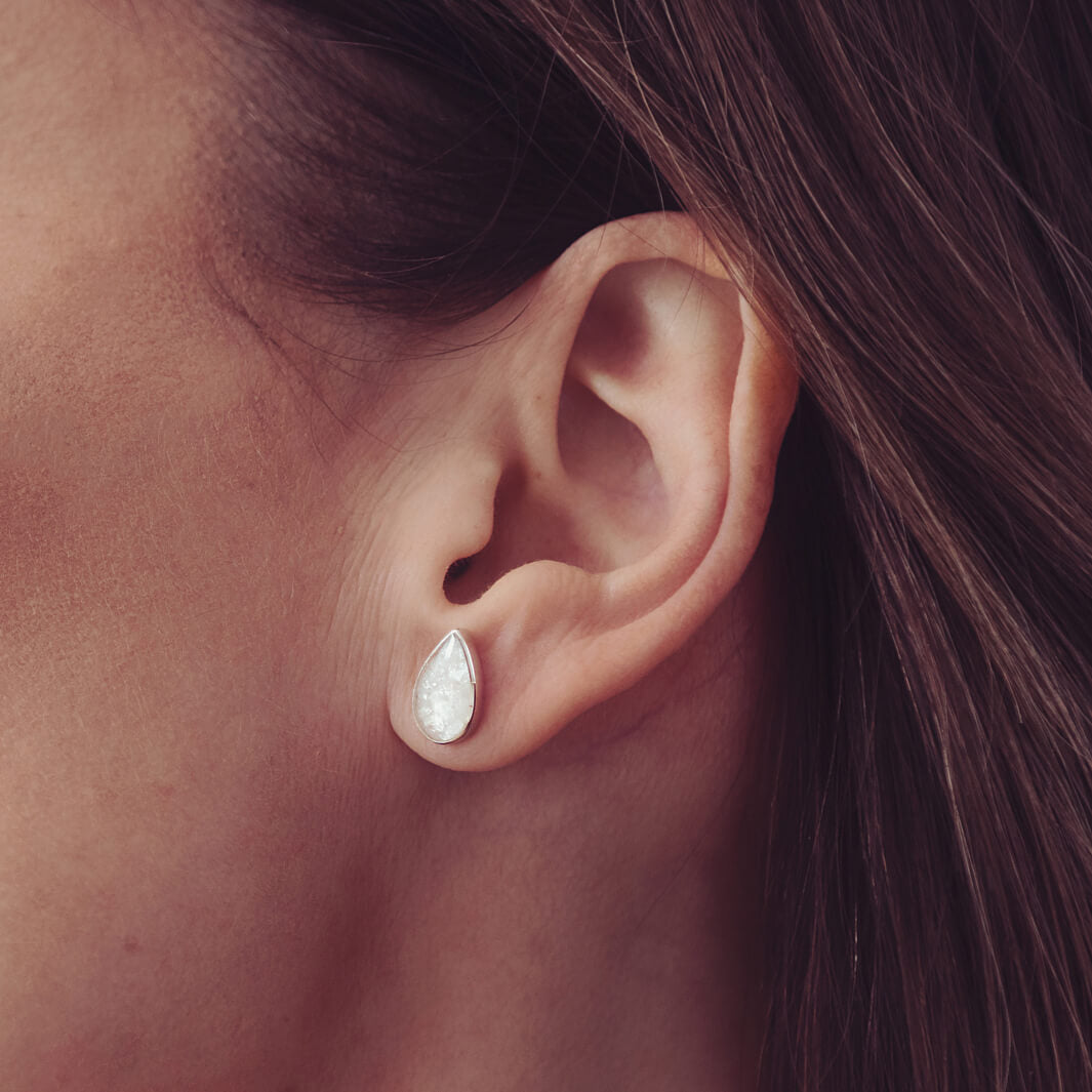 Cremation Ashes Teardrop Earrings with blue crystal, being worn in a ladies ear