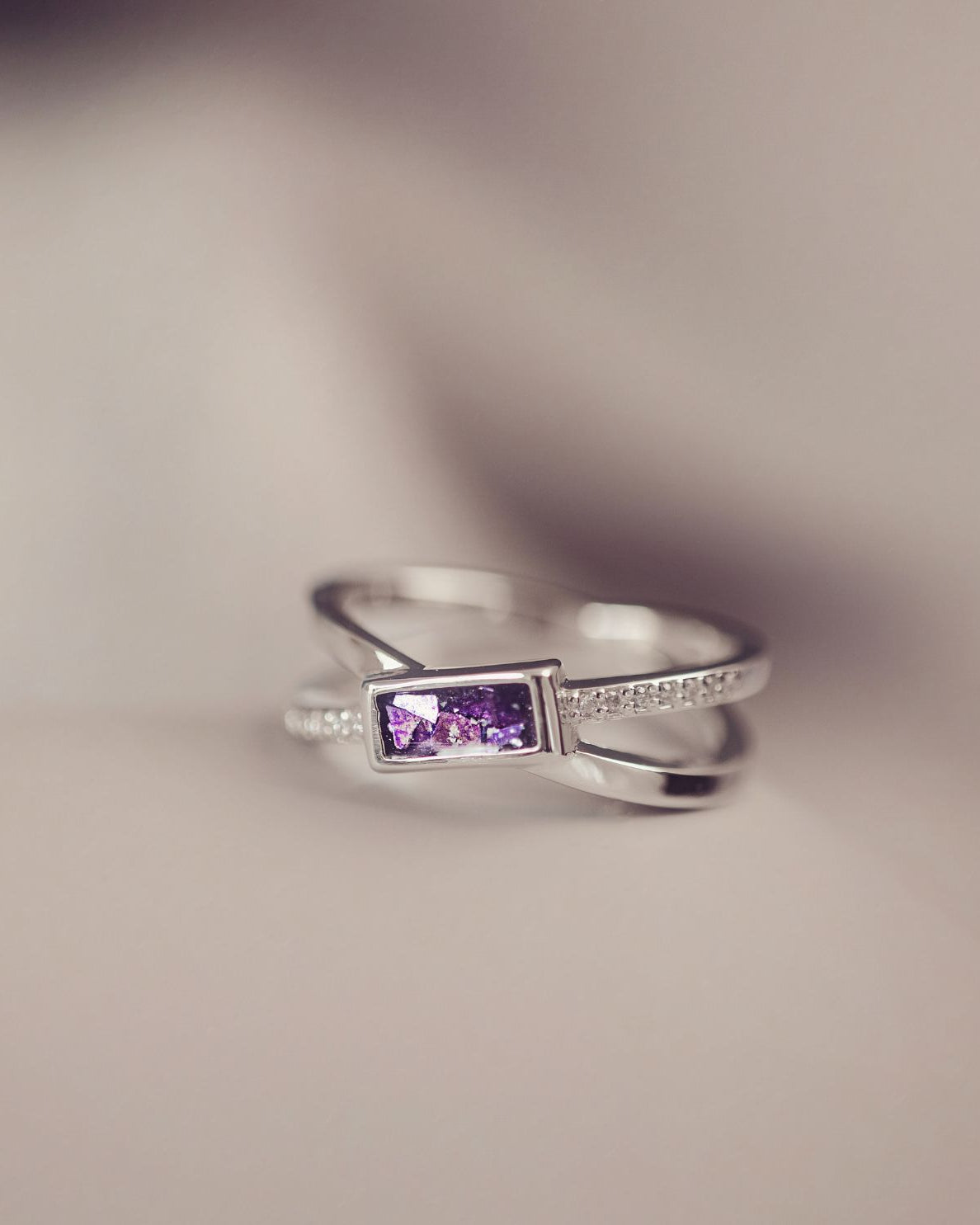 Silver ring with a purple gemstone on a blurred background