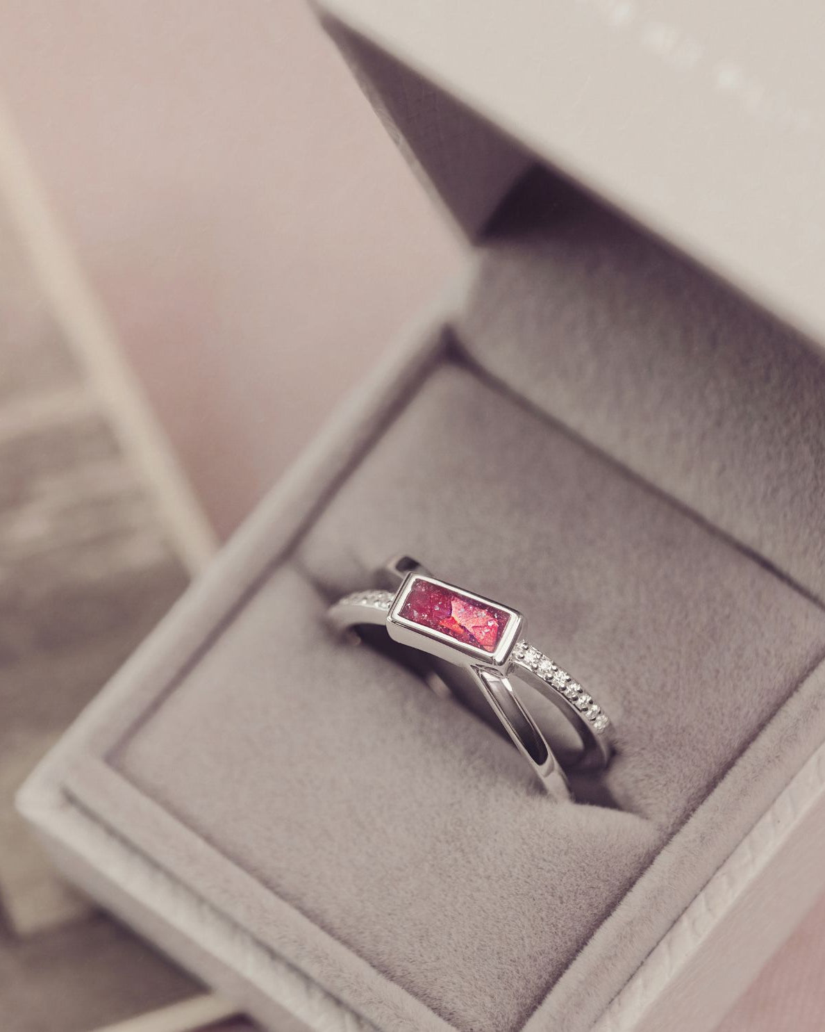 Silver ring with a red gemstone in a jewelry box