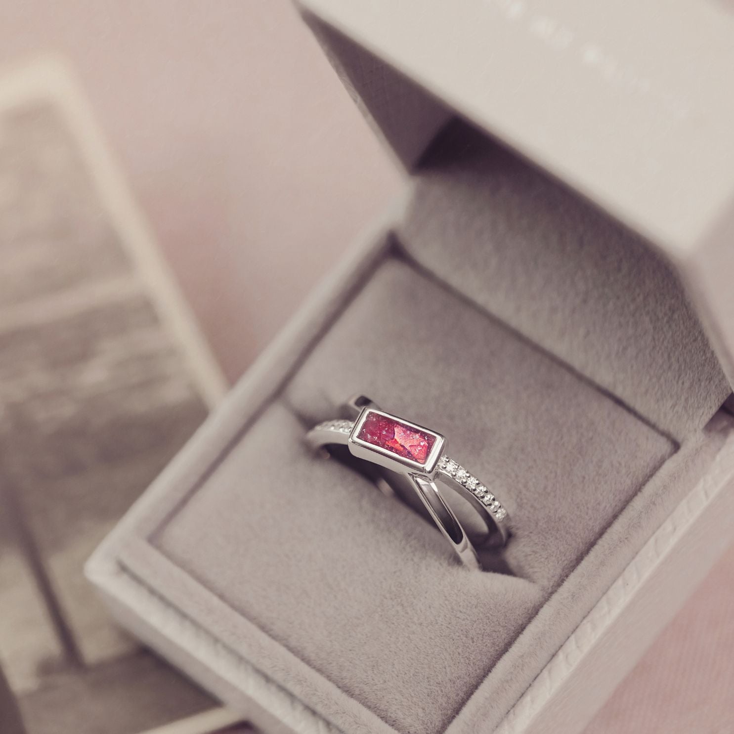 Silver ring with a red gemstone in a jewelry box