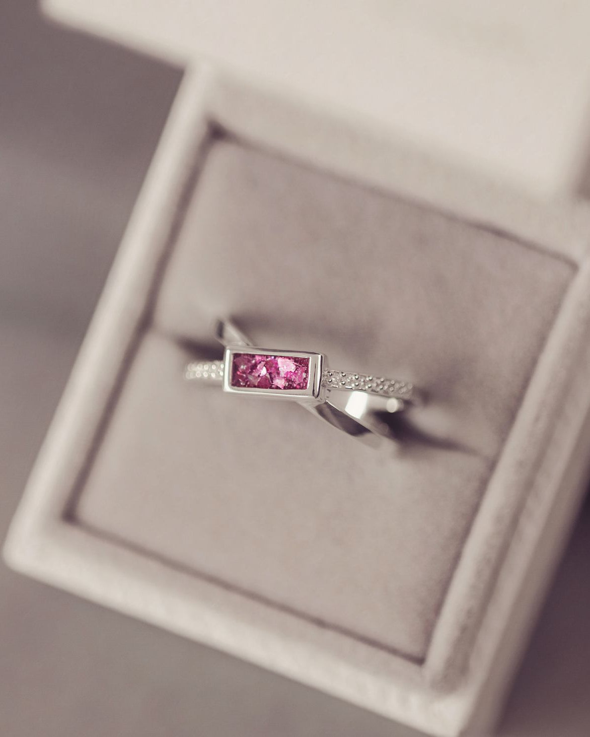 Silver ring with a pink gemstone in a jewelry box