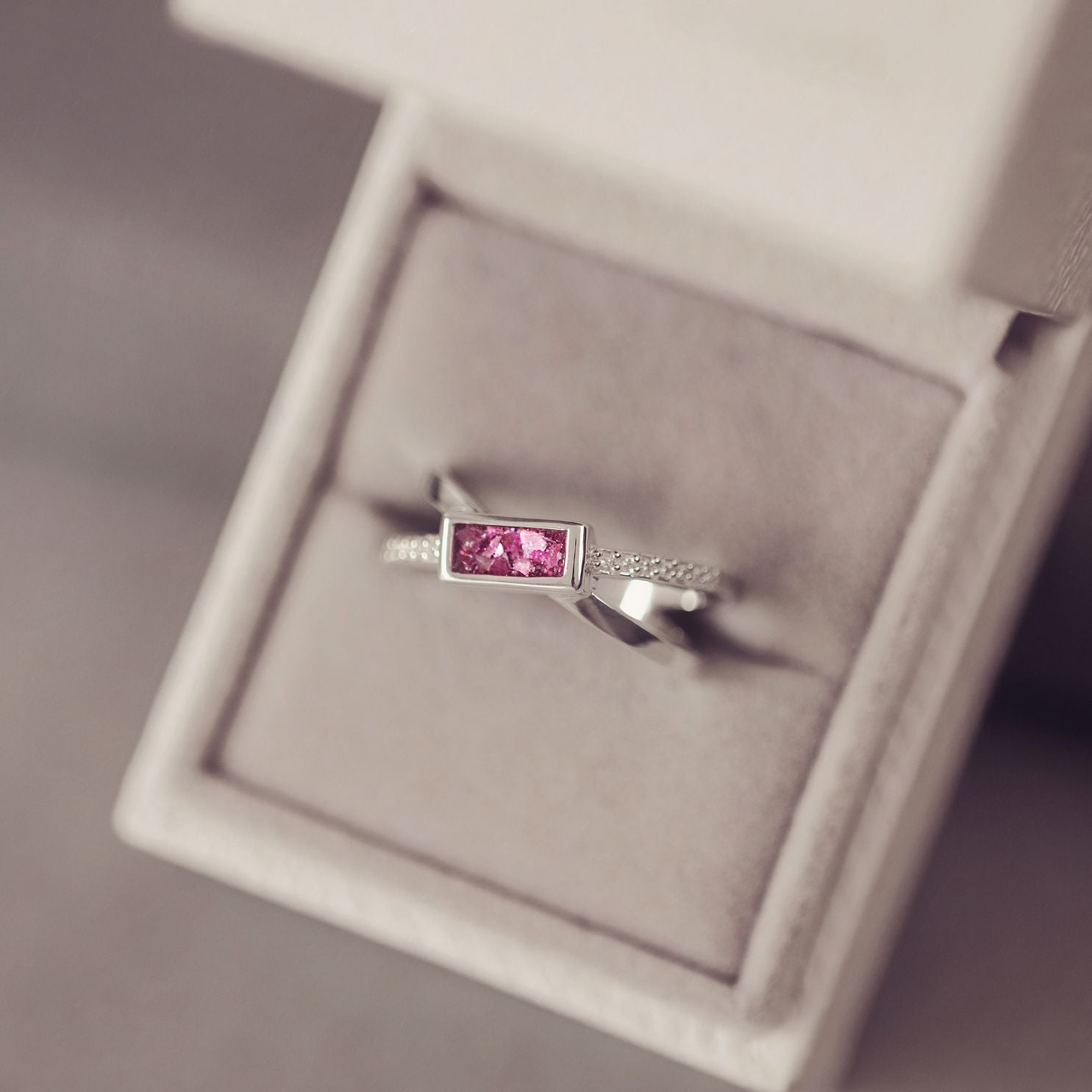 Silver ring with a pink gemstone in a jewelry box