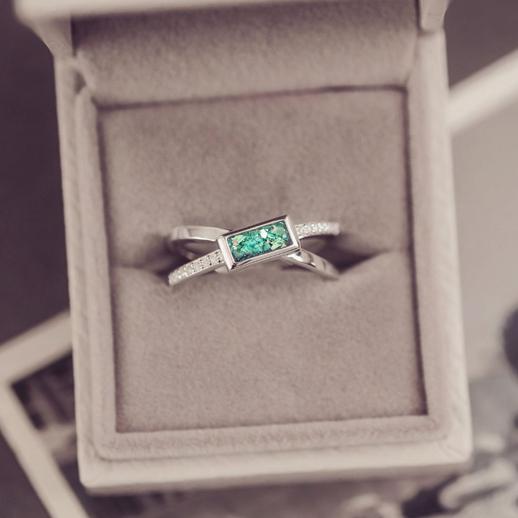 Silver ring with a green gemstone in a jewelry box