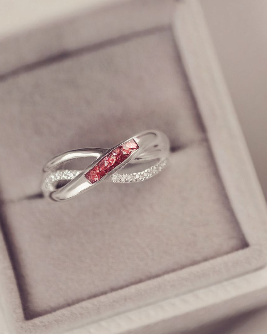 Silver ring with red gemstones in a gray jewelry box