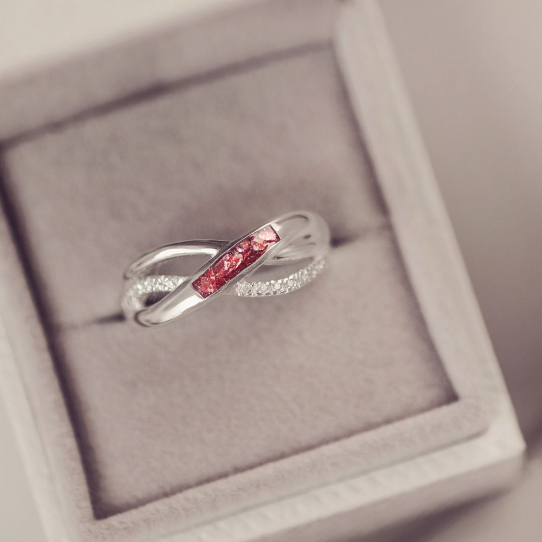 Silver ring with red gemstones in a gray jewelry box