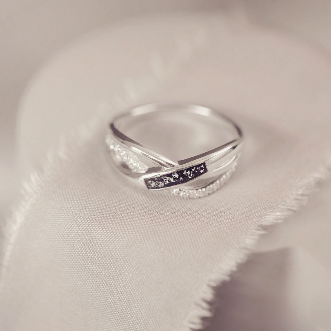 Silver ring with a small black inlay on a soft fabric background