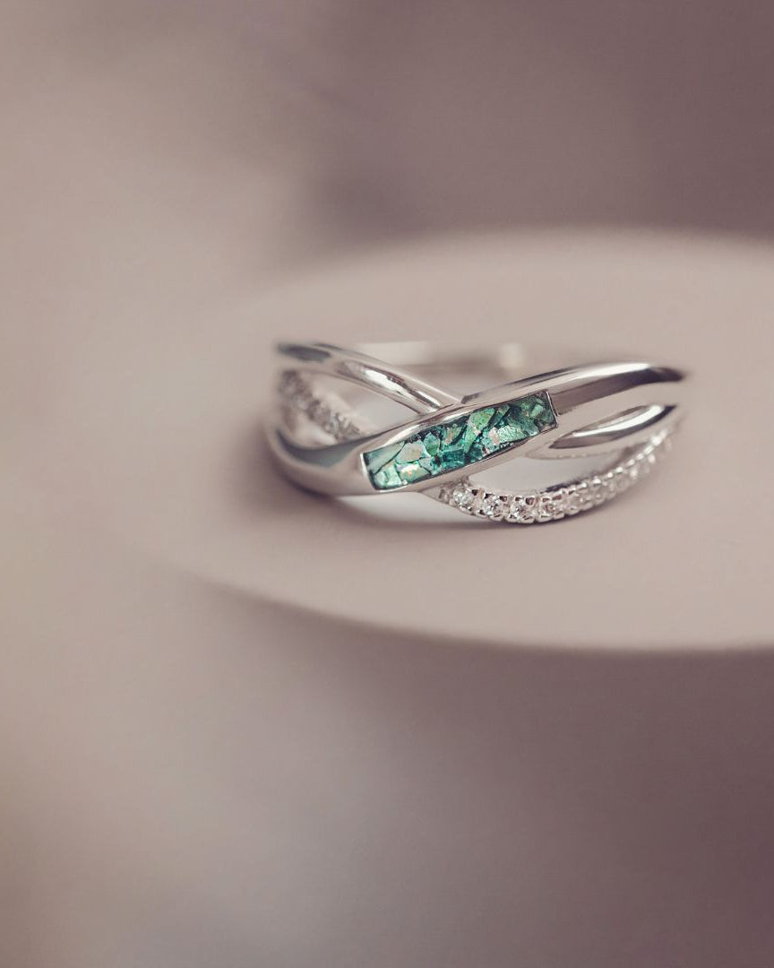 Silver ring with green gemstone on a blurred background